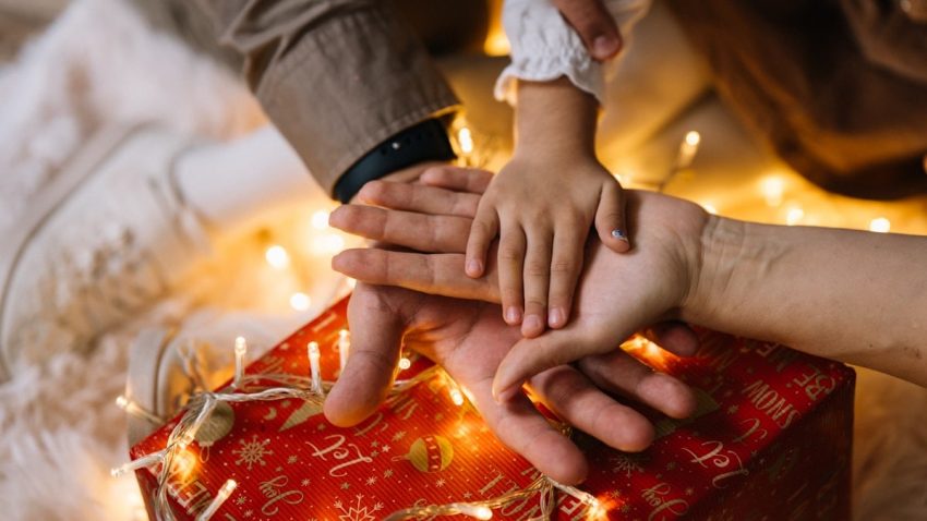 A group of people stacking their hands over a gift
