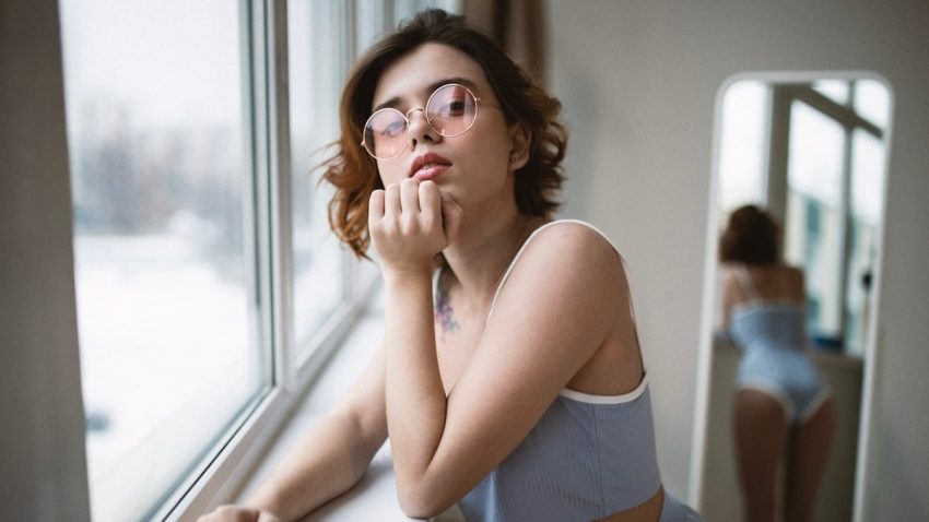 a woman with glasses looking out of a window